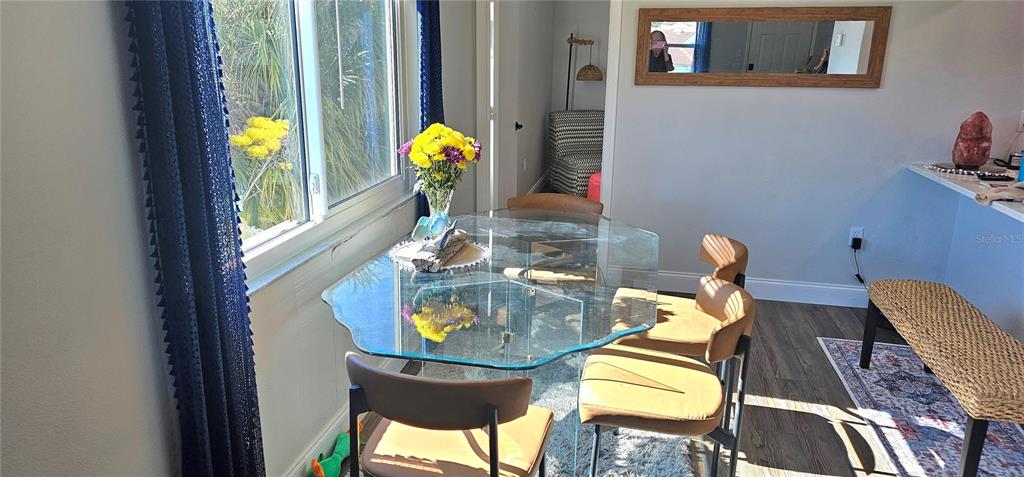 A dining area features a glass table, four chairs, a woven bench, and a large window — 3775 59TH AVENUE W UNIT 3775, BRADENTON, FL