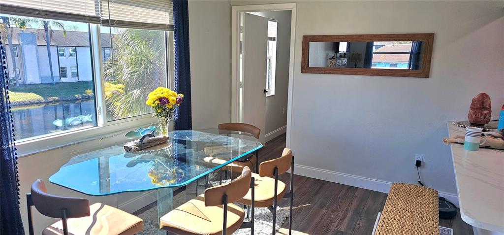 A dining area features a glass table, four chairs, a mirror, and a waterfront view — 3775 59TH AVENUE W UNIT 3775, BRADENTON, FL