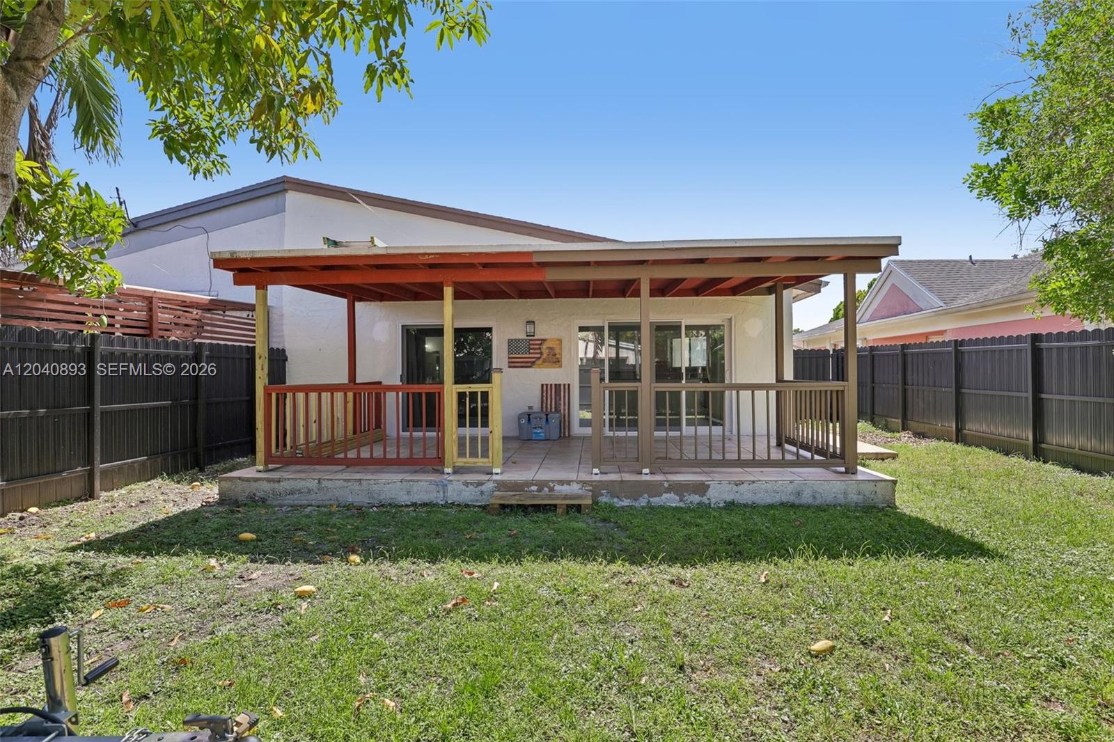 A backyard patio features a partially painted wooden pergola and a tiled concrete slab — 9709 SW 146th Ct, Miami FL 33186, MIAMI, FL
