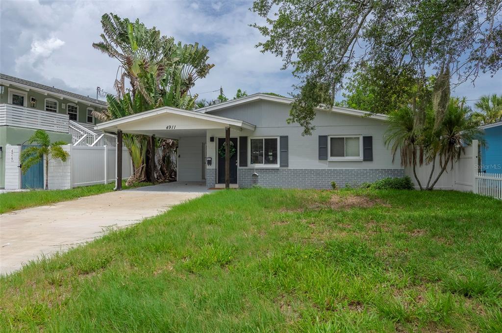 A single-story house with a gray exterior, a front carport, and a grassy front yard — 4911 CHANCELLOR STREET NE, ST PETERSBURG, FL