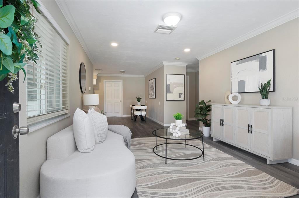 A modern living room features a curved white sofa, glass coffee table, and light wood sideboard — 4911 CHANCELLOR STREET NE, ST PETERSBURG, FL