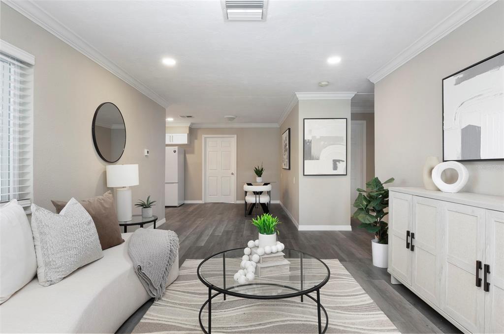 A living room features light gray walls, wood-look flooring, a white sofa, and a glass coffee table — 4911 CHANCELLOR STREET NE, ST PETERSBURG, FL