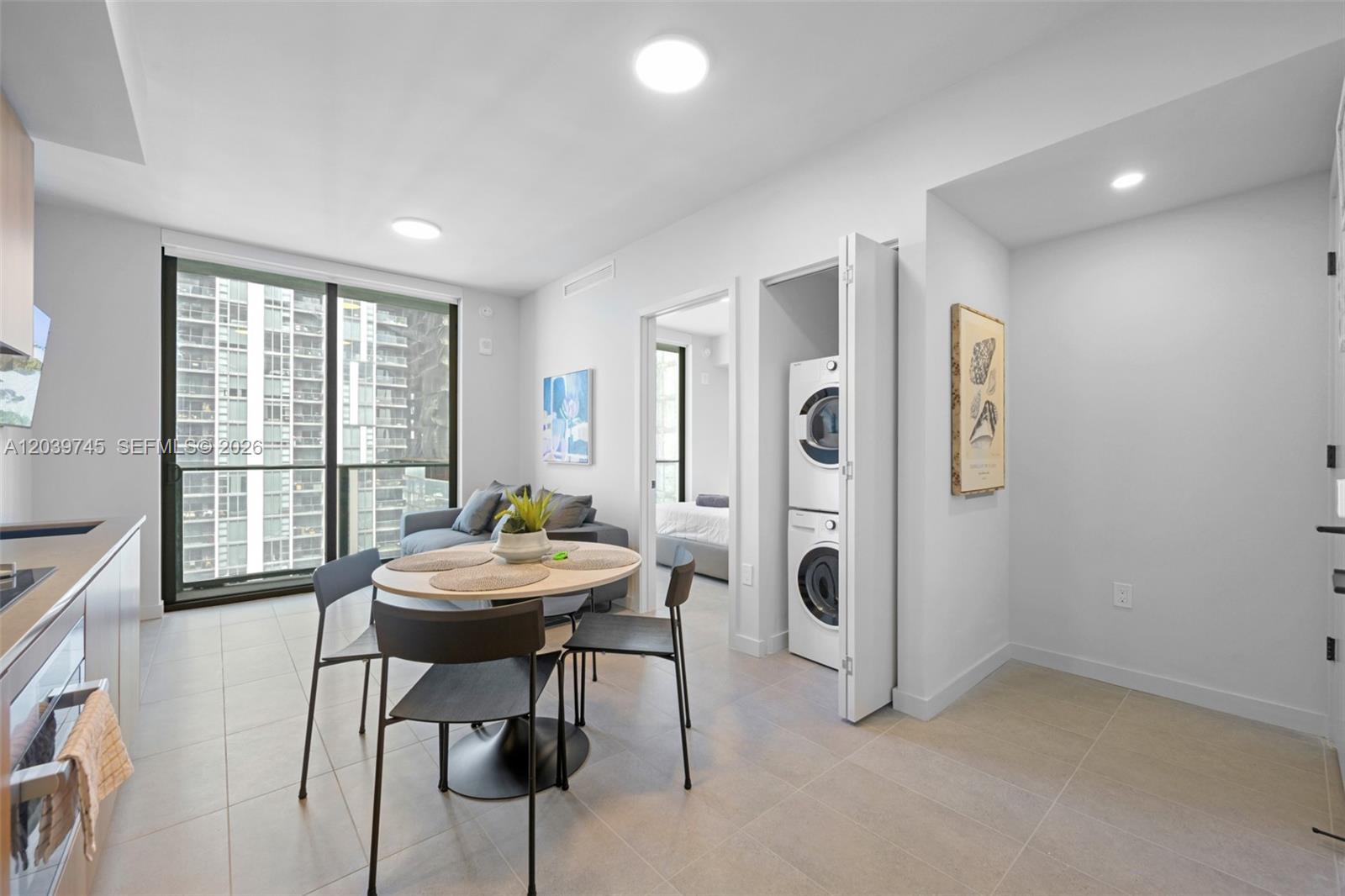 A modern apartment living area features a dining table, laundry closet, and floor-to-ceiling windows — 121 NE 5th St # 3006, Miami FL 33132, MIAMI, FL