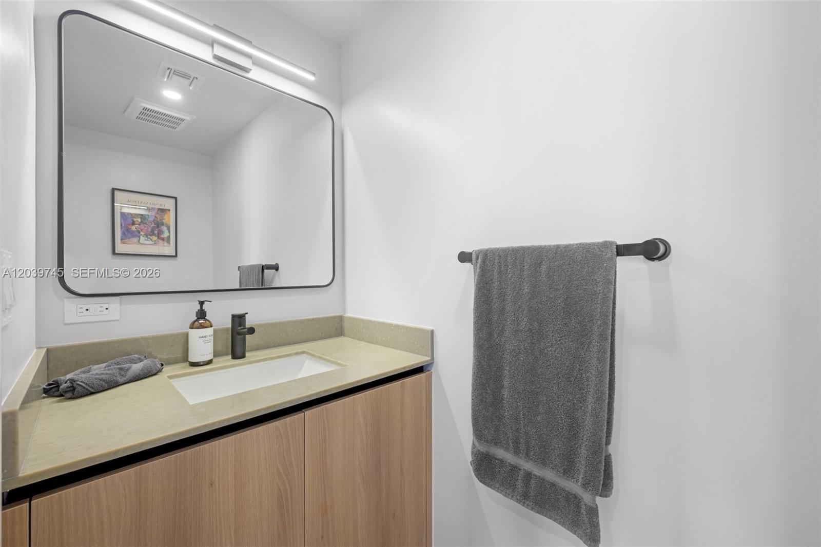 A modern bathroom features a light wood vanity, a rectangular mirror, and a gray towel — 121 NE 5th St # 3006, Miami FL 33132, MIAMI, FL