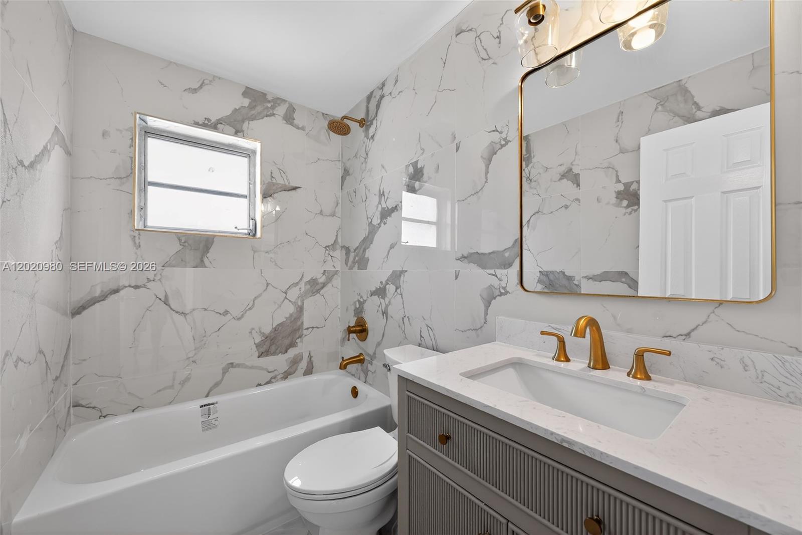 A bathroom features marble-patterned wall tiles, a grey vanity, and gold-toned fixtures — 145 SW 30TH CT # B208, Miami FL 33135, MIAMI, FL