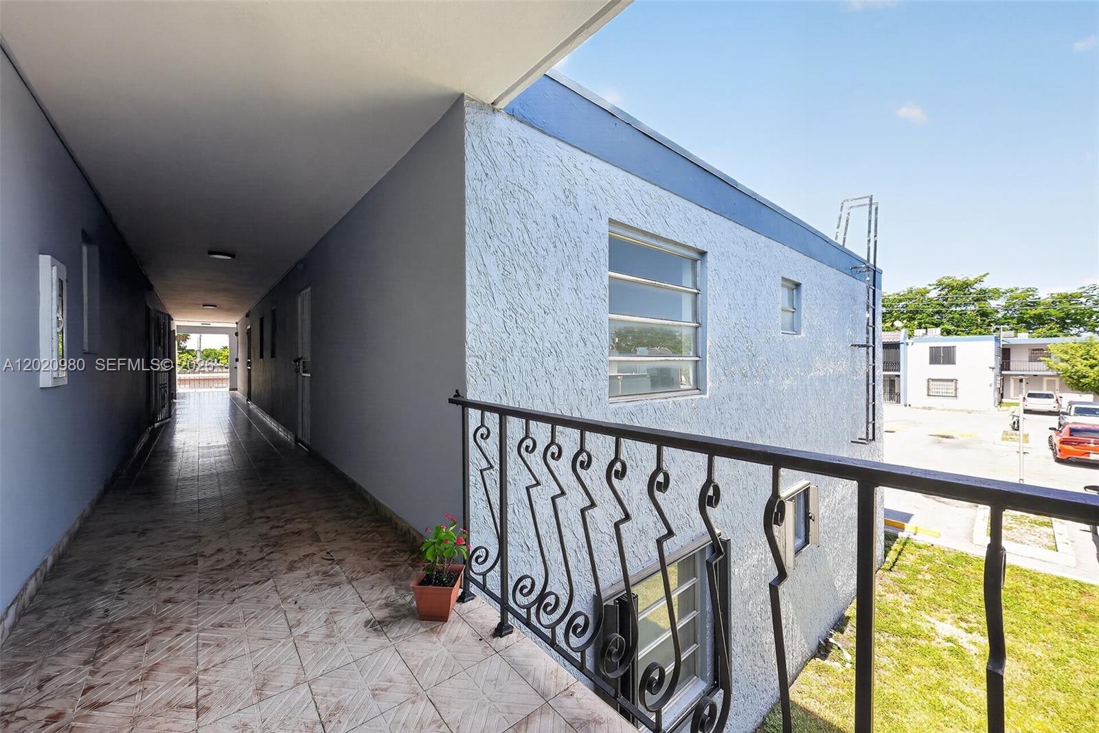 An outdoor walkway with tile flooring and a decorative metal railing overlooks a parking lot — 145 SW 30TH CT # B208, Miami FL 33135, MIAMI, FL