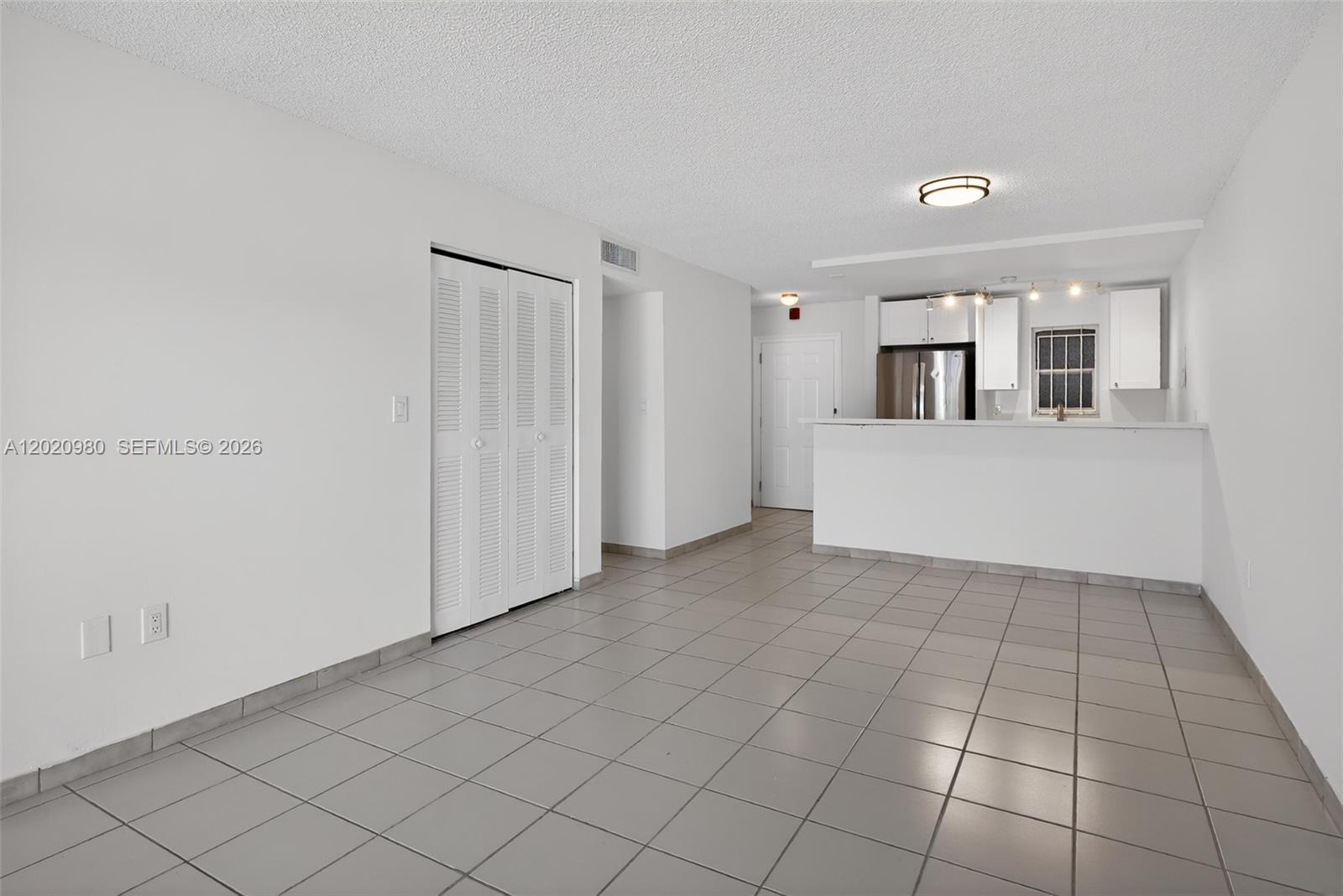 An open-concept living area features white walls, gray tile flooring, and a kitchen pass-through — 145 SW 30TH CT # B208, Miami FL 33135, MIAMI, FL