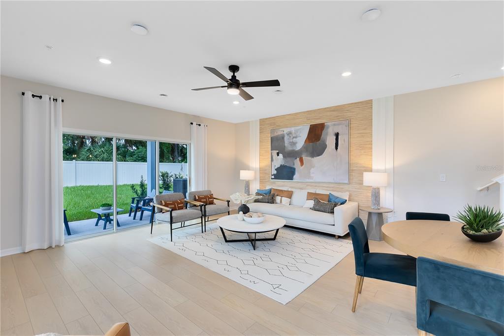 A bright living room features light wood floors, a textured accent wall, and sliding glass doors — 472 BERYL COVE, SANFORD, FL