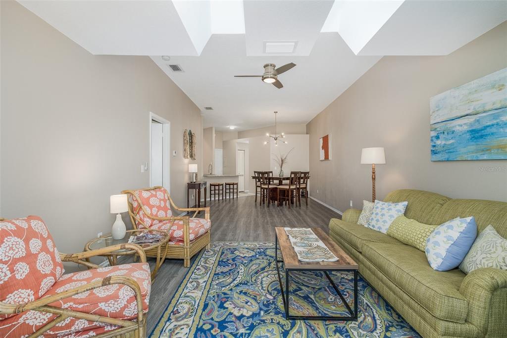 A living room with a green sofa, patterned armchairs, and an open dining area — 3843 GOLDFINCH COURT, PALM HARBOR, FL