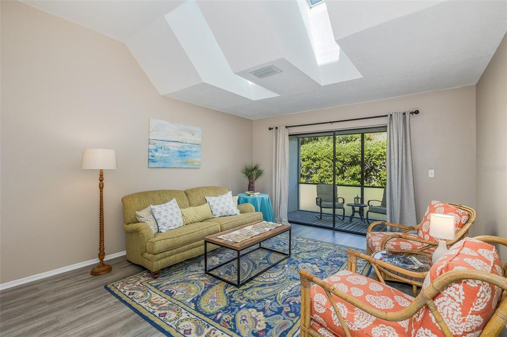 A living room features a green sofa, patterned armchairs, a rug, and a vaulted ceiling — 3843 GOLDFINCH COURT, PALM HARBOR, FL