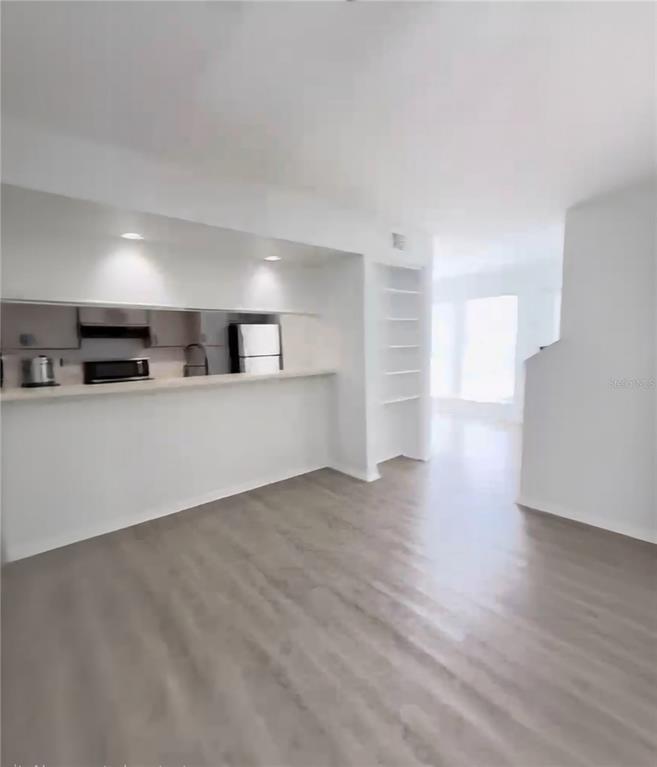 A kitchen with a breakfast bar opens into a living area with light wood flooring — 3982 CRAYRICH CIRCLE UNIT C4, ORLANDO, FL