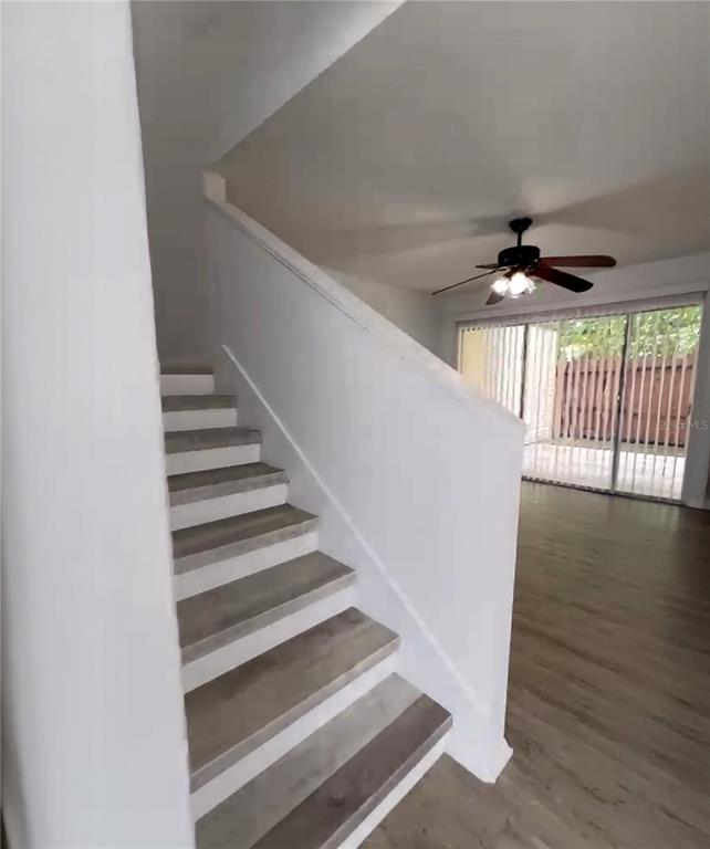 A staircase with wood-look treads leads upward next to a living area with a ceiling fan — 3982 CRAYRICH CIRCLE UNIT C4, ORLANDO, FL