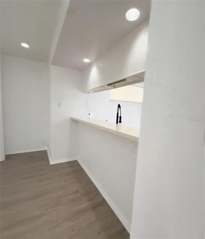 A kitchen features a white breakfast bar, recessed lighting, and light-colored wood-look flooring — 3982 CRAYRICH CIRCLE UNIT C4, ORLANDO, FL