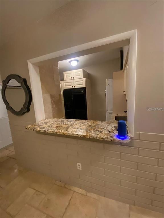 A kitchen pass-through window features a granite countertop above a painted brick wall — 270 110TH AVENUE, TREASURE ISLAND, FL