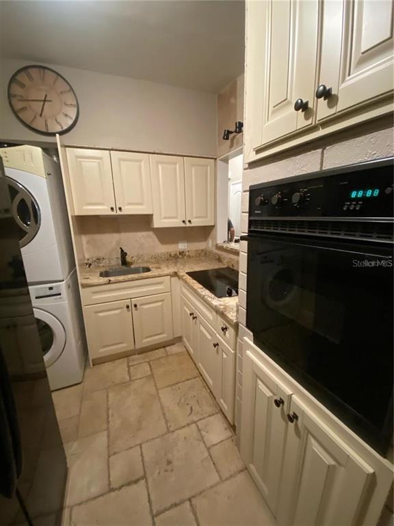 A kitchen features cream-colored cabinets, a built-in oven, a small sink, and stone tile flooring — 270 110TH AVENUE, TREASURE ISLAND, FL