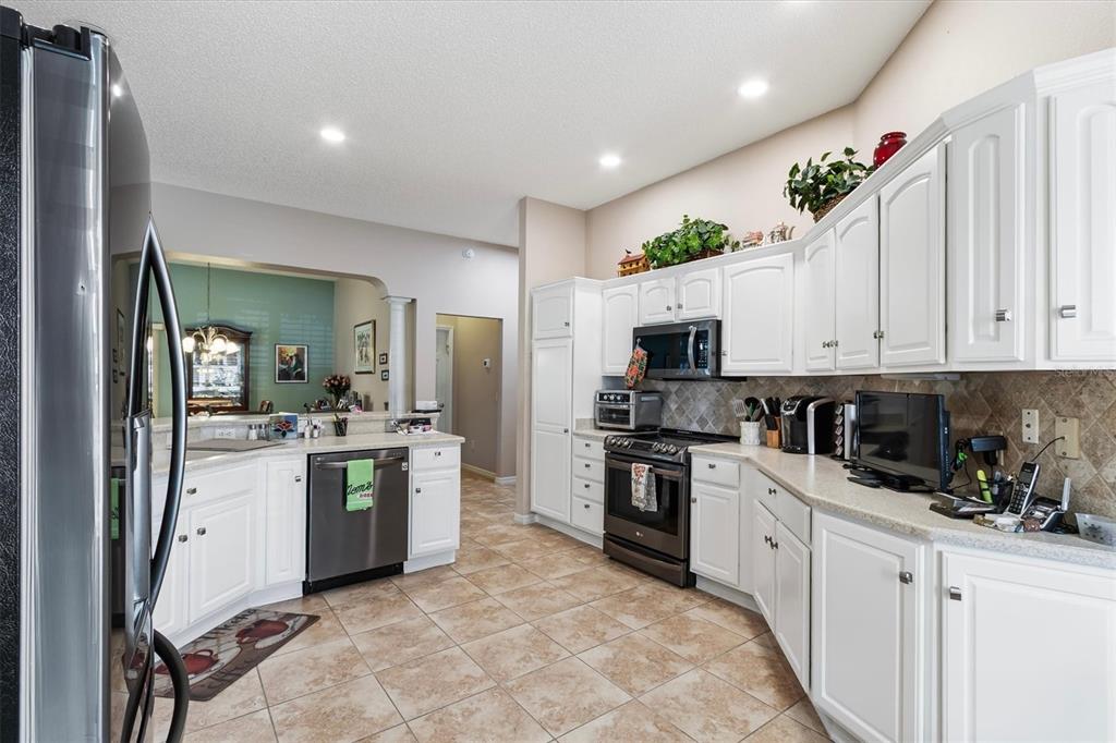 A kitchen with white cabinets, stainless steel appliances, and beige tile flooring — 2314 CALLAWAY DRIVE, THE VILLAGES, FL