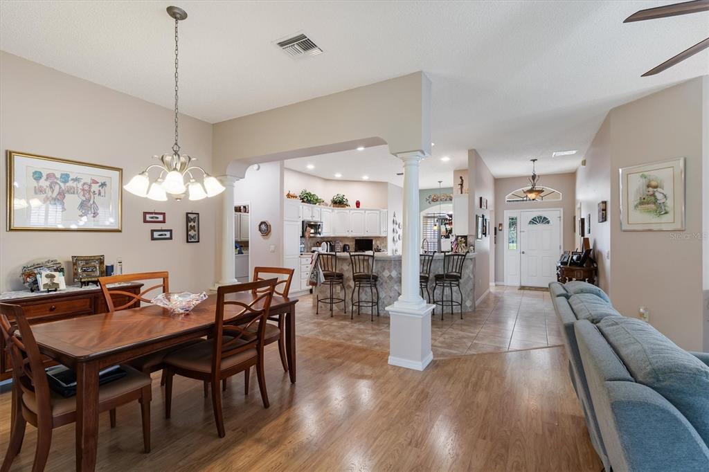 An open-concept dining area and kitchen with wood flooring, a breakfast bar, and white cabinetry — 2314 CALLAWAY DRIVE, THE VILLAGES, FL