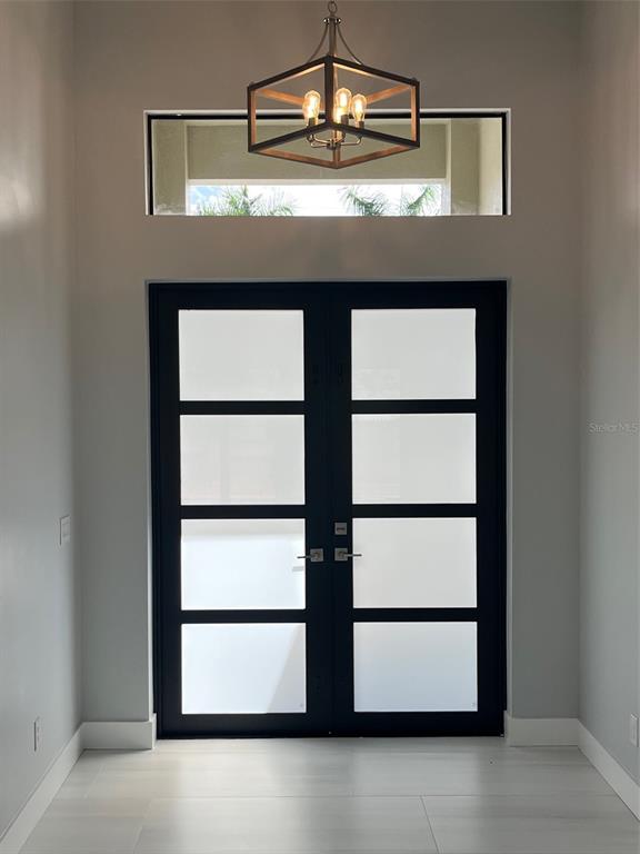 An entryway features double glass doors with black frames, a transom window, and a chandelier — 17653 VELLUM CIRCLE, PUNTA GORDA, FL