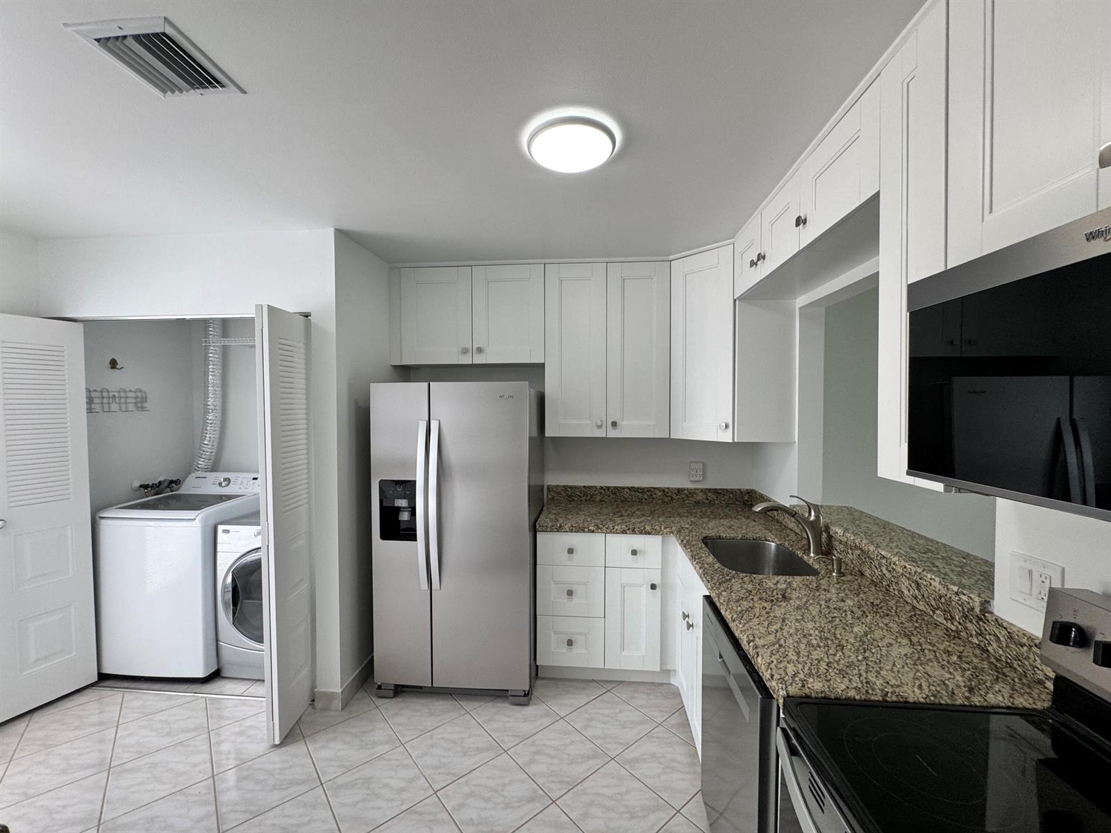 A kitchen features white cabinets, granite countertops, stainless steel appliances, and an adjacent laundry closet — 6846 Moonlit Drive, Delray Beach FL 33446, DELRAY BEACH, FL