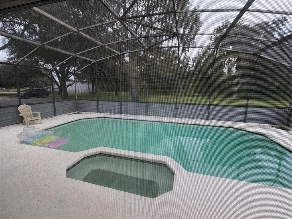 A screened-in pool and spa area with a concrete deck and a single chair — 6828 STATE ROAD 33, CLERMONT, FL