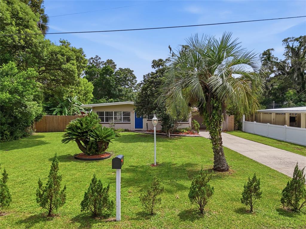 A single-story house with a blue front door, a palm tree, and a grassy front yard — 722 TEMPLE AVENUE, ORANGE CITY, FL