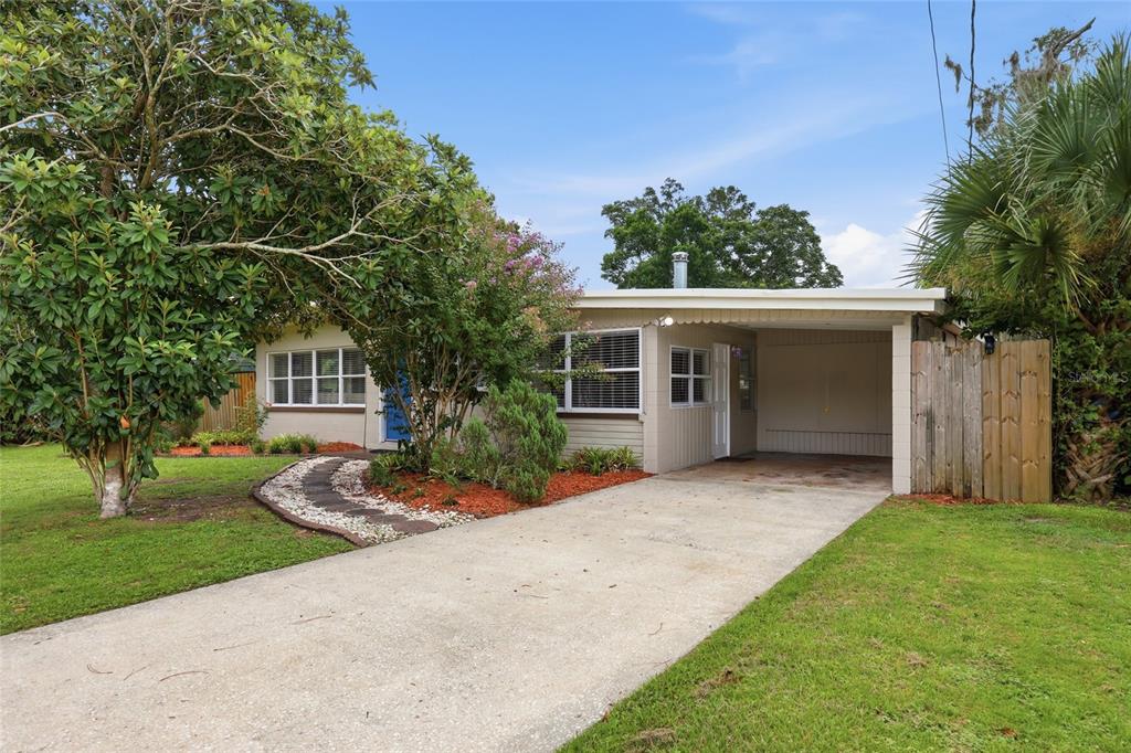 A single-story house with a concrete driveway, attached carport, and a landscaped front yard — 722 TEMPLE AVENUE, ORANGE CITY, FL