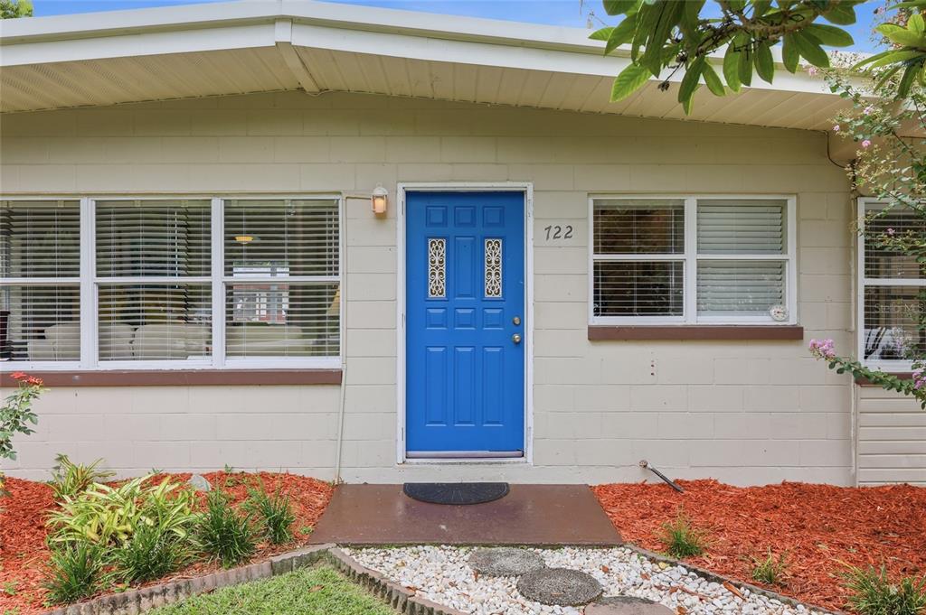 A bright blue front door with decorative glass panels on a light-colored concrete block house — 722 TEMPLE AVENUE, ORANGE CITY, FL