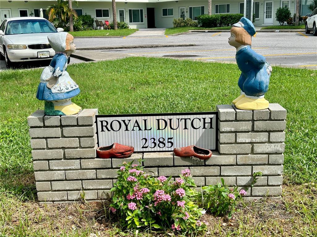 A brick sign featuring two Dutch-themed statues and two wooden clogs sits in a lawn — 2386 SUMATRAN WAY UNIT 68, CLEARWATER, FL