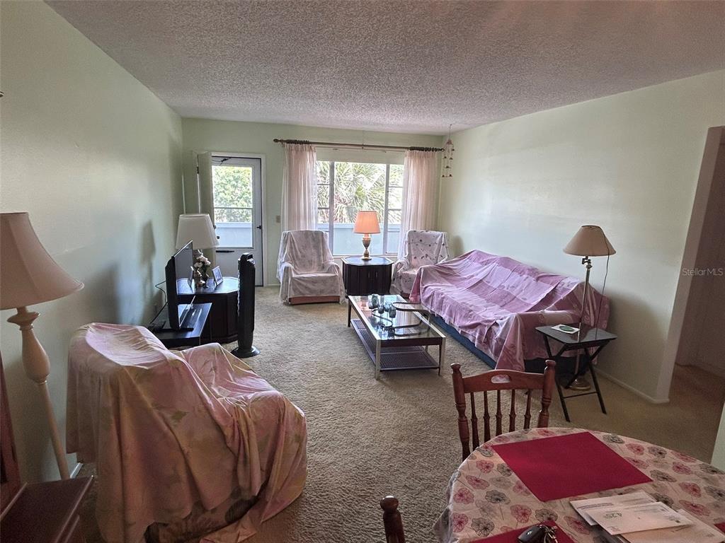 A living room with a blue sofa, coffee table, and an adjacent dining area — 2386 SUMATRAN WAY UNIT 68, CLEARWATER, FL