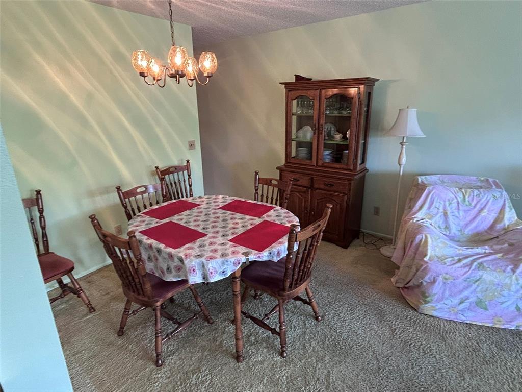 A living room features beige carpet, a blue sofa, a floral armchair, and a coffee table — 2386 SUMATRAN WAY UNIT 68, CLEARWATER, FL