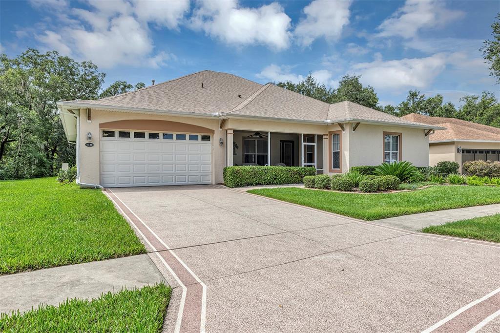A single-story house with a beige stucco exterior, a two-car garage, and a screened porch — 4348 ANTIETAM CREEK TRAIL, LEESBURG, FL