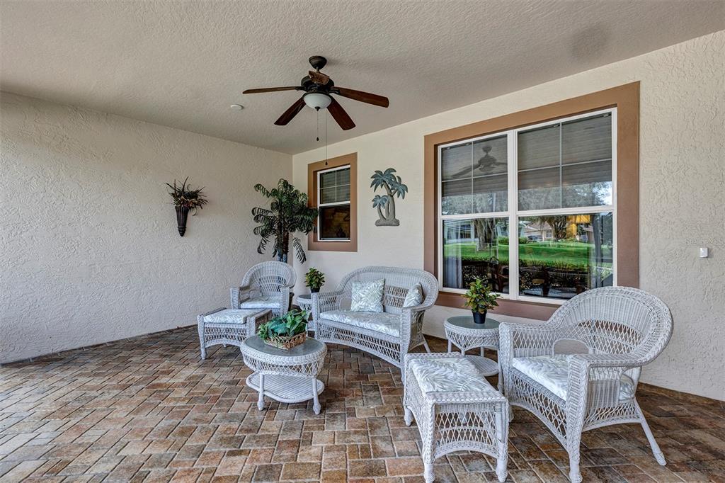 A covered patio features wicker furniture, a ceiling fan, and brick pavers — 4348 ANTIETAM CREEK TRAIL, LEESBURG, FL