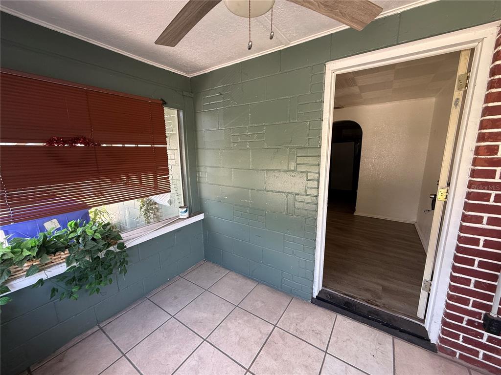 A covered porch features green painted block walls, tiled flooring, and a ceiling fan — 1117 BRACK STREET, KISSIMMEE, FL
