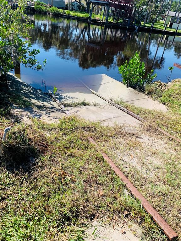 A concrete boat ramp leads into a canal with a wooden dock in the background — 5948 RIVERSIDE DRIVE, PORT ORANGE, FL