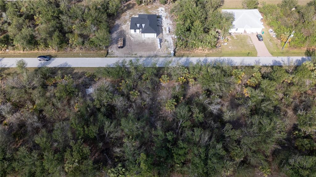 An aerial view shows a newly constructed house and a neighboring home along a road — 7051 LEGION STREET, PORT CHARLOTTE, FL