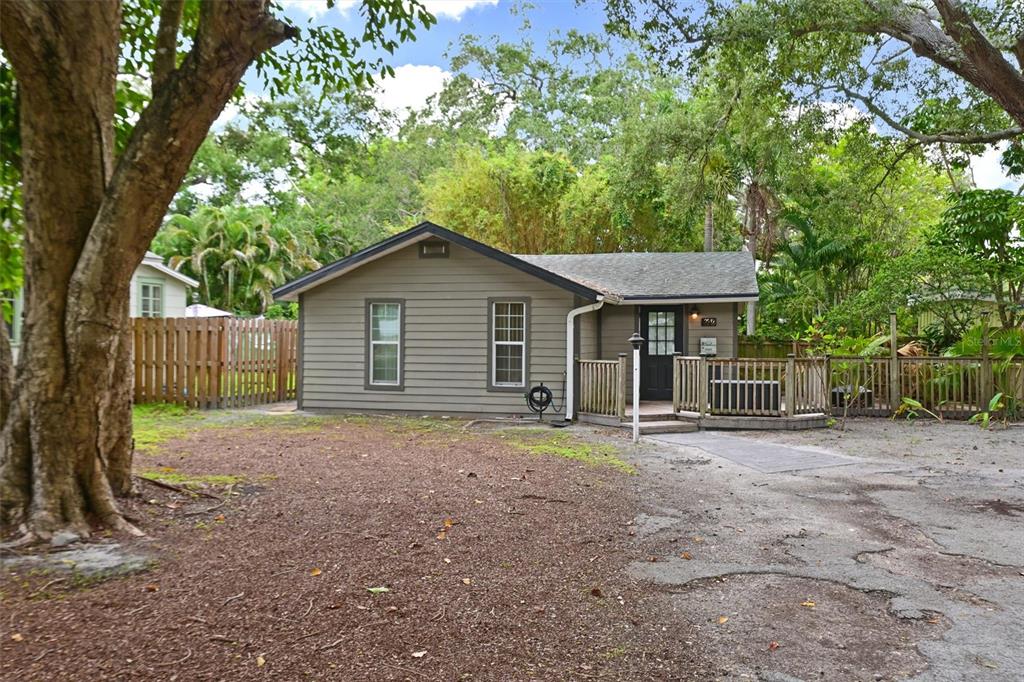 A single-story house with gray horizontal siding and a wooden deck sits among trees — 2212 11TH AVENUE W, BRADENTON, FL