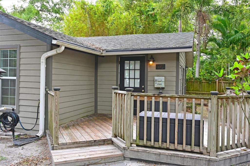 A wooden deck with a railing leads to the entrance of a gray house — 2212 11TH AVENUE W, BRADENTON, FL
