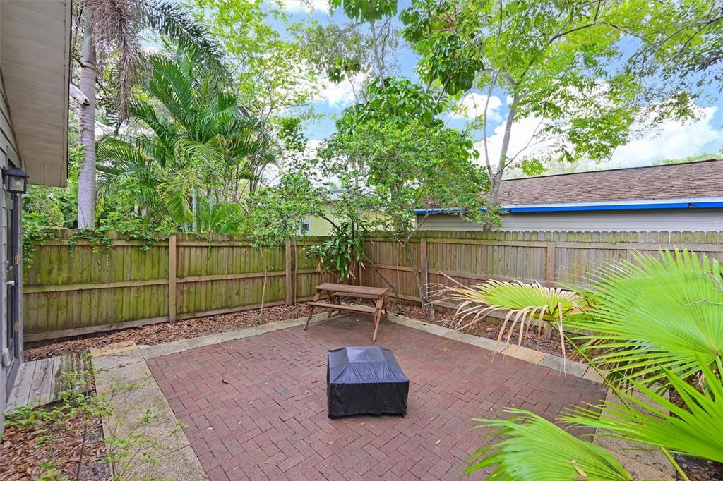 A brick patio features a small wooden picnic table and a covered fire pit — 2212 11TH AVENUE W, BRADENTON, FL