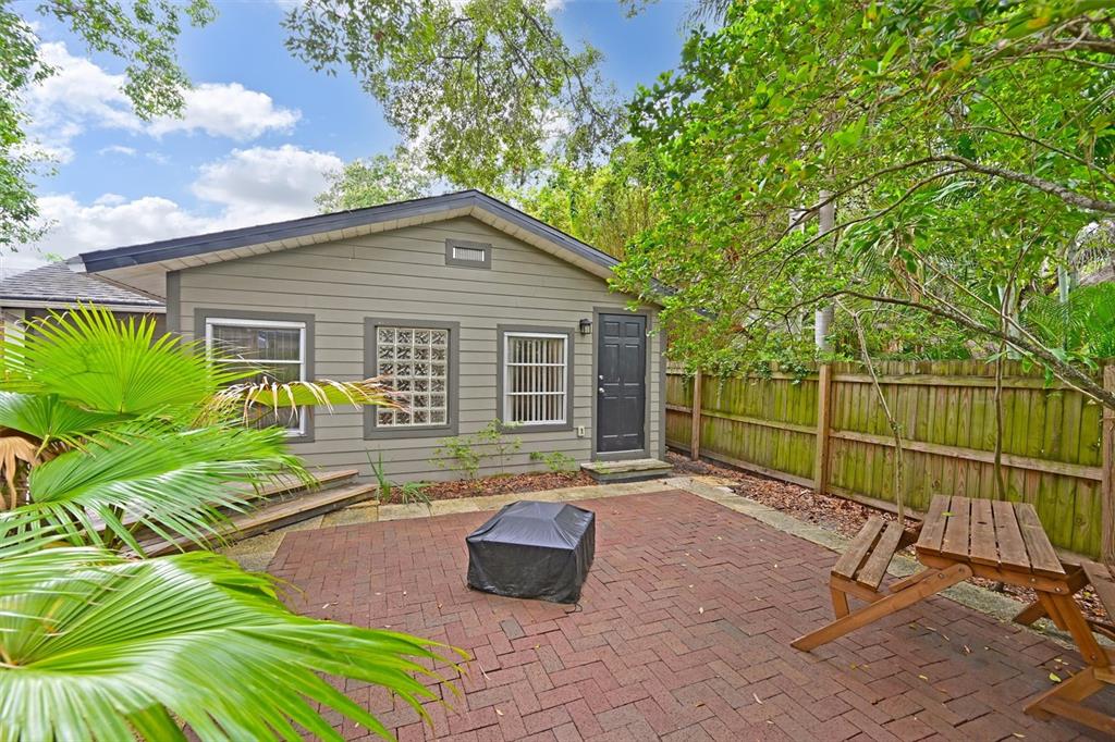 A brick patio with a fire pit sits in front of a gray detached building — 2212 11TH AVENUE W, BRADENTON, FL