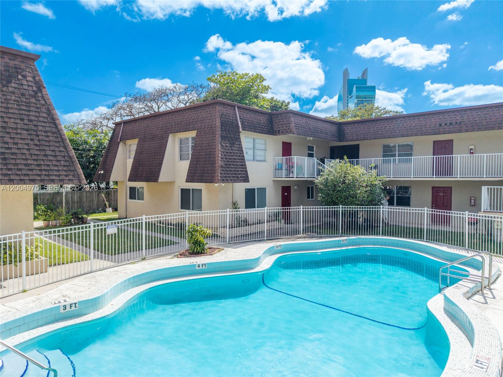 A swimming pool sits in front of a two-story apartment building with a brown roof — 4524 SW 54th St, Dania Beach FL 33314, DANIA BEACH, FL