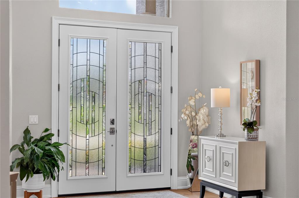 A white double front door with decorative glass panels stands in a bright entryway — 7311 BIRDS NEST COURT, YALAHA, FL
