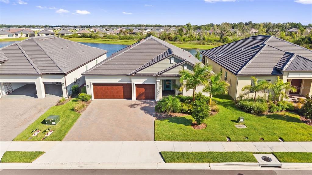 An aerial view shows a suburban house with a tiled roof, driveway, and backyard pond — 12211 VIOLET JASPER DRIVE, PARRISH, FL