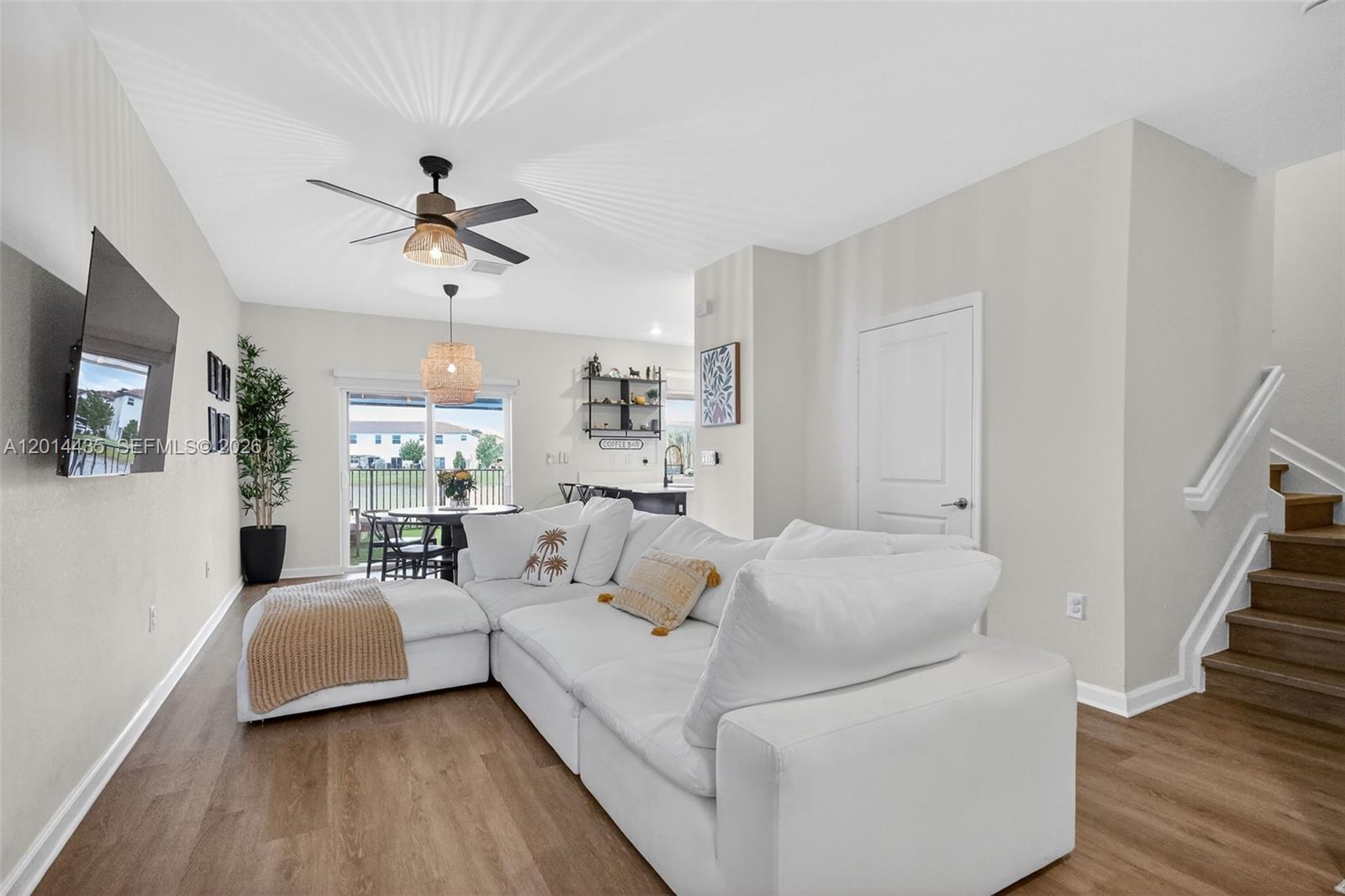 A white sectional sofa sits in a living room with wood floors and stairs — 12808 NW 22nd Pl, Miami FL 33167, MIAMI, FL