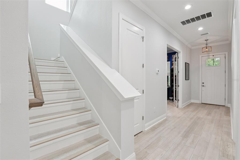 A bright entryway features light wood-look flooring, a staircase with white risers, and a front door — 714 S LOIS AVENUE, TAMPA, FL