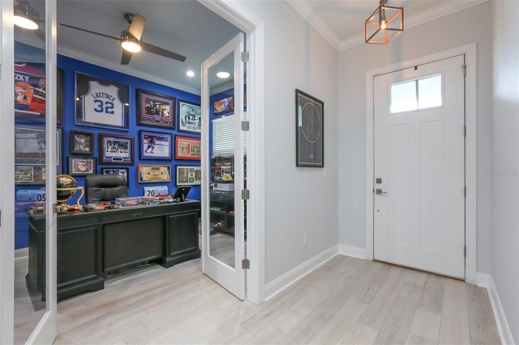 A home office with a blue accent wall and sports memorabilia sits beside an entryway — 714 S LOIS AVENUE, TAMPA, FL