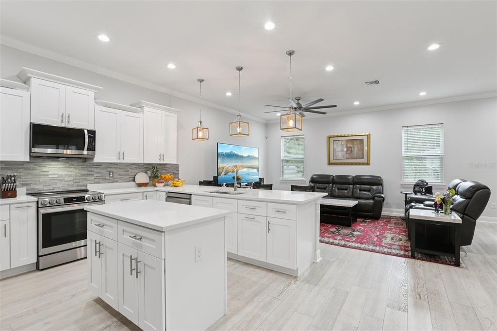 An open-concept kitchen and living area features white cabinetry, a central island, and wood flooring — 714 S LOIS AVENUE, TAMPA, FL