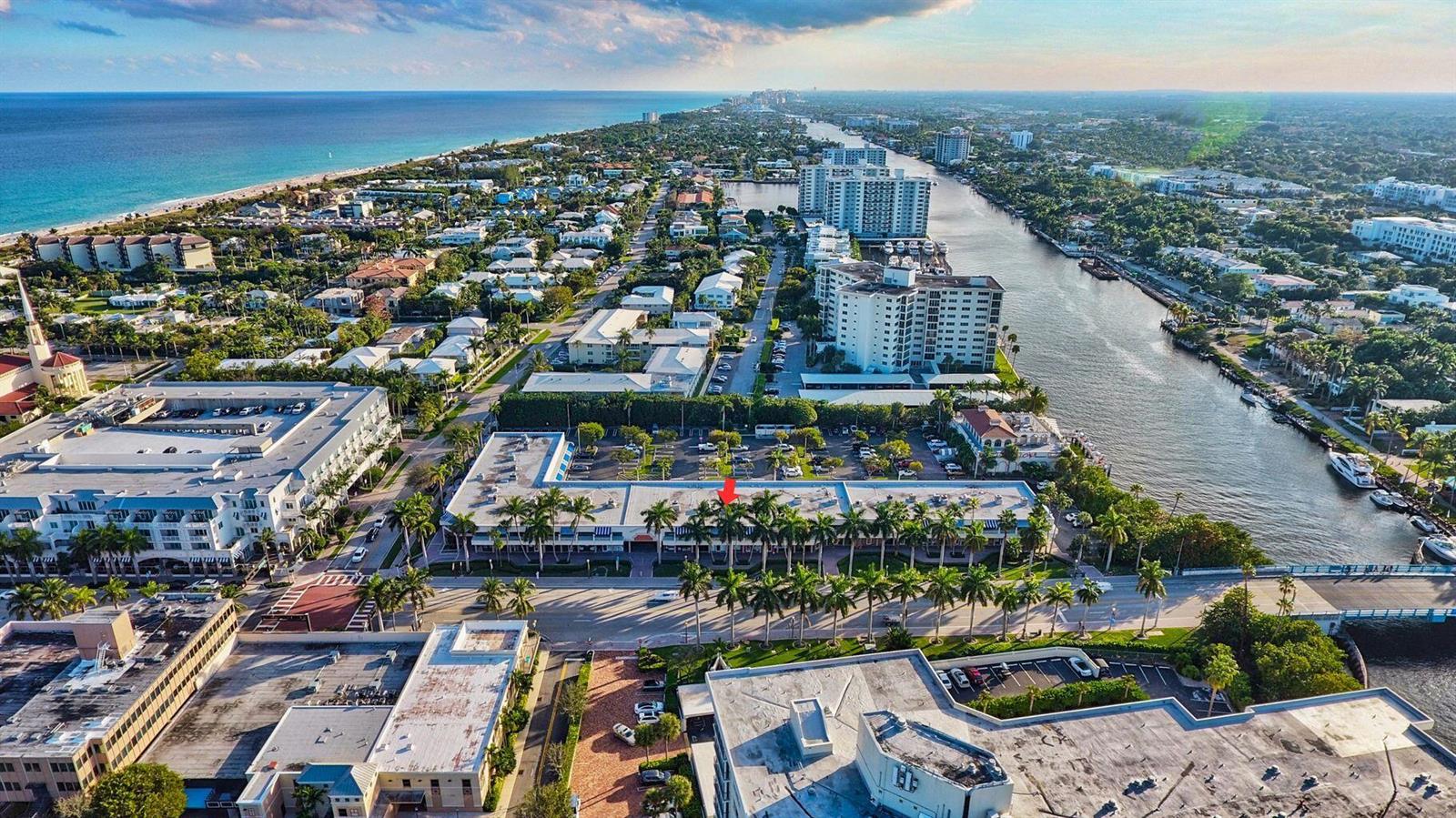 Aerial view of a commercial building with palm trees near a canal and the ocean — 900 E Atlantic Avenue # 12, Delray Beach FL 33483, DELRAY BEACH, FL