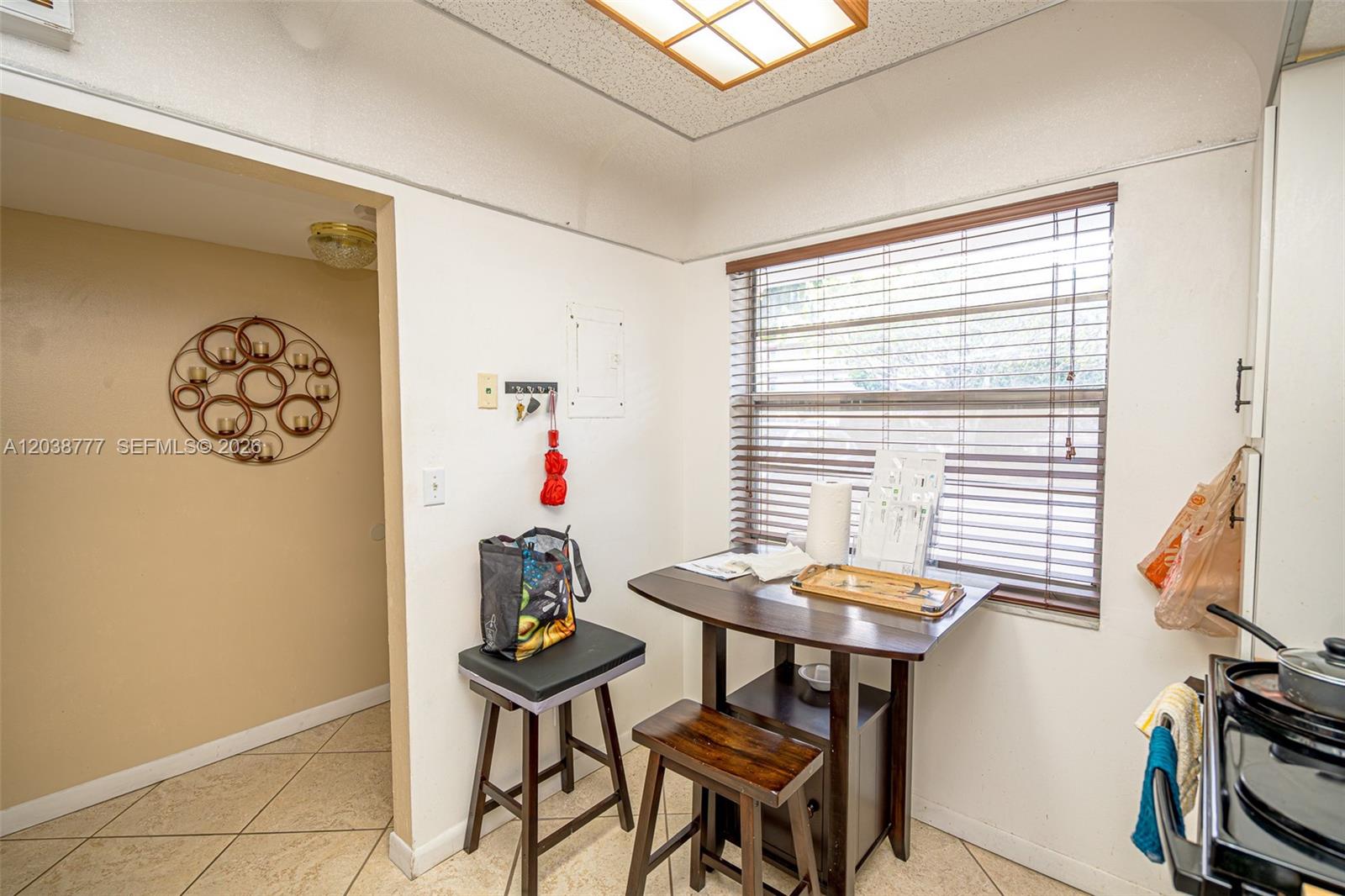A small kitchen features a dining table with two stools, a window, and tile flooring — 3531 Inverrary Dr # 108, Lauderhill FL 33319, LAUDERHILL, FL