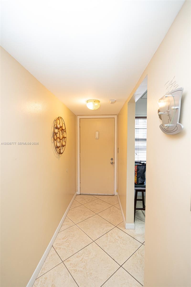 A tiled entryway features a light-colored door, beige walls, and decorative wall art — 3531 Inverrary Dr # 108, Lauderhill FL 33319, LAUDERHILL, FL