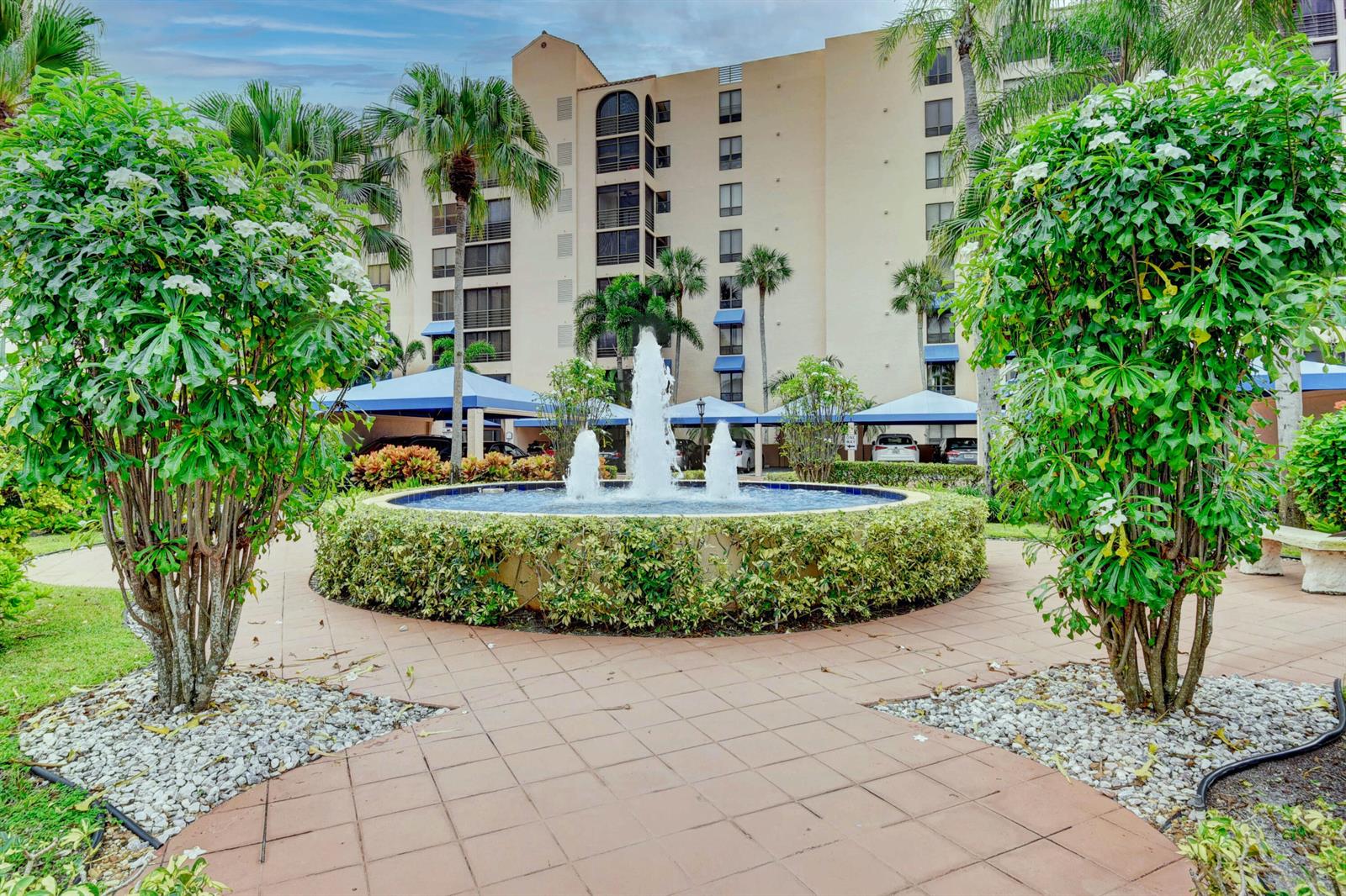 A circular fountain sits in a courtyard in front of a multi-story apartment building — 7194 Promenade Drive # 202, Boca Raton FL 33433, BOCA RATON, FL